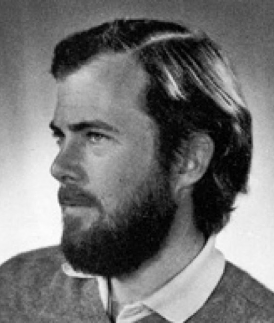 Photo en noir et blanc d'un homme aux cheveux mi-longs à la barbe et à la moustache.